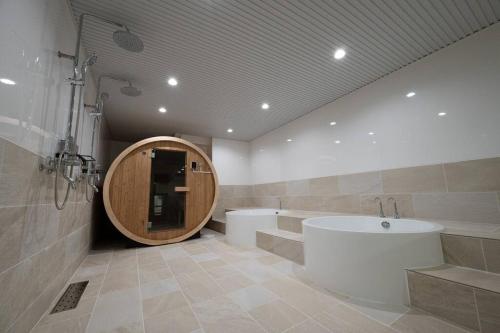 a bathroom with a large tub and a sink at tomo 非日常の暮らし 広い浴室サウナ付き 寝室6つ ベッド11台 関西空港直通の最寄り駅 in Osaka