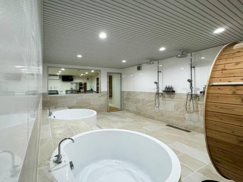 a large bathroom with two sinks and a large tub at tomo 非日常の暮らし 広い浴室サウナ付き 寝室6つ ベッド11台 関西空港直通の最寄り駅 in Osaka