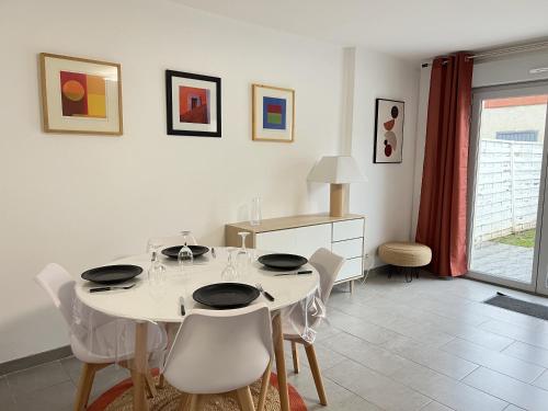 une salle à manger blanche avec une table et des chaises blanches dans l'établissement La Tannerie des Bourgeois, à Calais