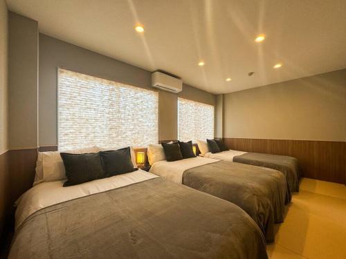 a room with three beds in it with a window at tomo 非日常の暮らし 広い浴室サウナ付き 寝室6つ ベッド11台 関西空港直通の最寄り駅 in Osaka