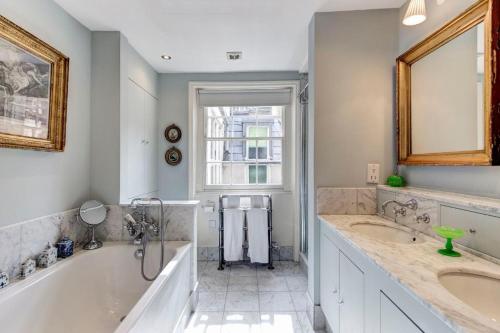 uma casa de banho com 2 lavatórios e uma grande banheira em Promient Royal Victorian Villa - Sleeps 12 em Londres