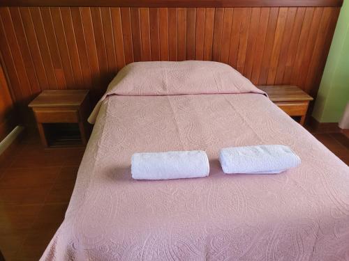 Dos toallas están sentadas en una cama rosa. en Hotel Restaurante Minas Cocha, en Chavín de Huantar