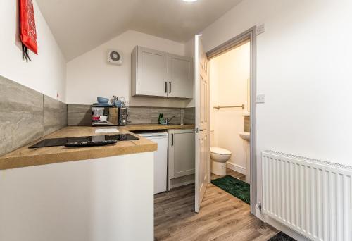 une cuisine avec des placards blancs et des toilettes dans l'établissement Stay Sleep Rest - Derby Road, à Nottingham