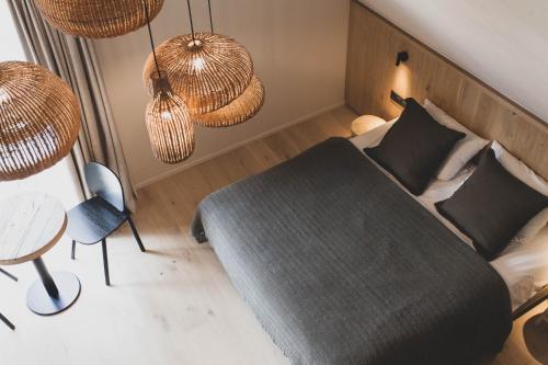 a bedroom with a bed and a table and chandeliers at Wood (Forestia) in Theux