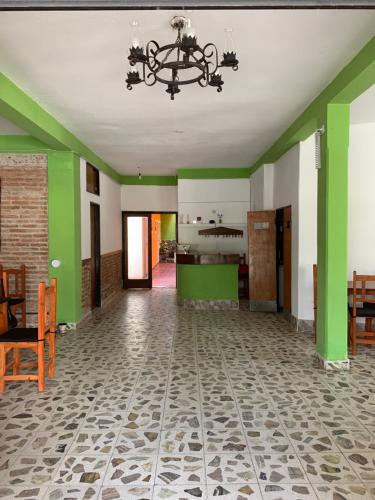 una sala de estar con paredes verdes y una lámpara de araña. en HOSTAL EL REY en Cafayate