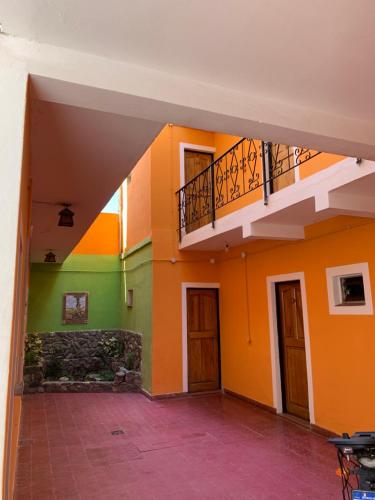 Habitación vacía con paredes de color naranja y verde. en HOSTAL EL REY en Cafayate