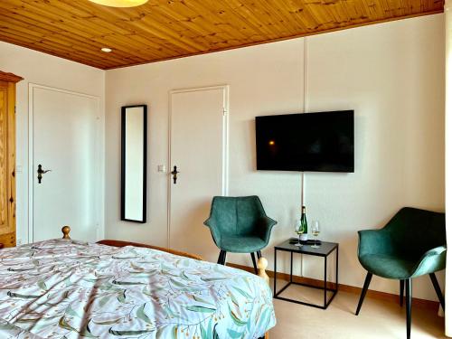 a bedroom with a bed and two chairs and a television at Pension 1595 im Weingut Botzet in Maring-Noviand