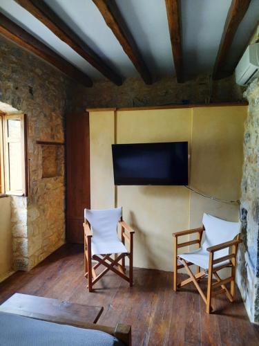 a room with two chairs and a flat screen tv at Studio Tsiliviani in Loukádhika
