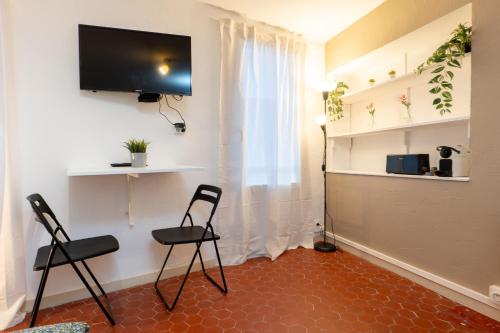 Cette chambre comprend deux chaises et une télévision à écran plat. dans l'établissement Magnifique studio cosy et calme, à Digne-Les-Bains