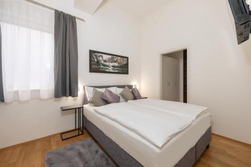a bedroom with a large white bed with a window at Appartement Tamino - City Appartement by Schladmingurlaub in Schladming
