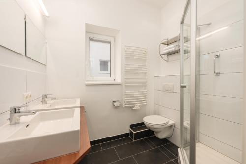 a white bathroom with a sink and a toilet at Appartement Tamino - City Appartement by Schladmingurlaub in Schladming