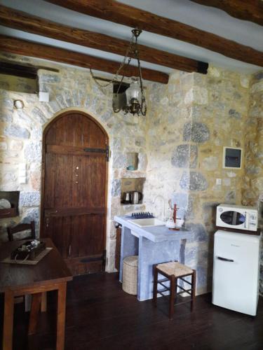 cocina con pared de piedra, fregadero y fogones en Studio Tsiliviani, en Loukádhika