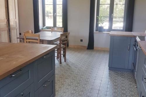 cocina con armarios azules, mesa y sillas en Chambre double à la campagne en Verchin