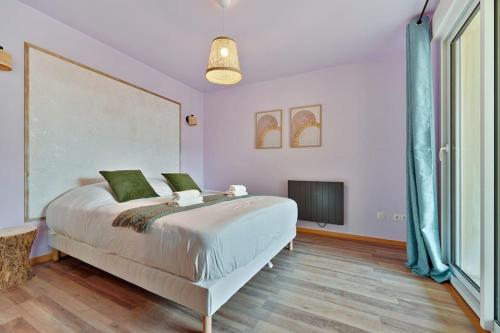 1 dormitorio con 1 cama blanca grande con almohadas verdes en Purple House, en Vigneux-sur-Seine
