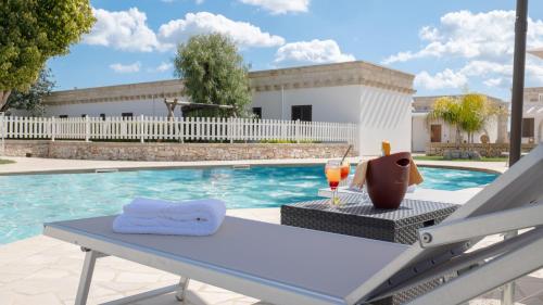 a table with a glass of wine next to a pool at Borgo Specchia Natural Resort in Specchia