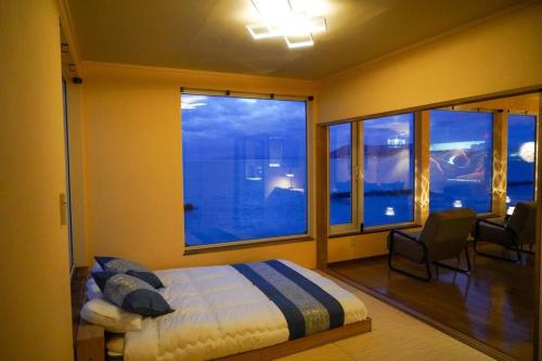 sypialnia z łóżkiem i dużym oknem w obiekcie Nesaki Native w mieście Hakodate