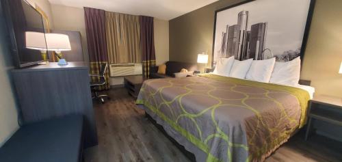 um quarto de hotel com uma cama grande e uma secretária em Super 8 by Wyndham Sterling Heights/Detroit Area em Sterling Heights