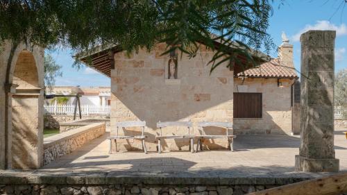 a building with two benches in front of it at Borgo Specchia Natural Resort in Specchia