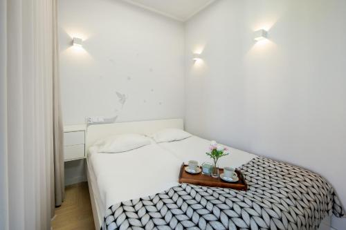 een witte slaapkamer met een bed en een dienblad met bloemen erop bij Apartment with Balcony and Parking by Renters in Krakau