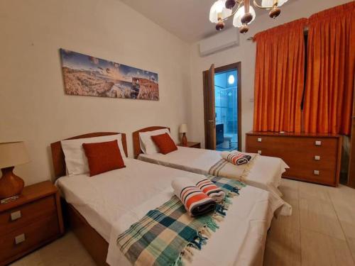 um quarto com 2 camas e um lustre em MIVE -Bugibba Modern Apartment next to main square em St. Paul's Bay