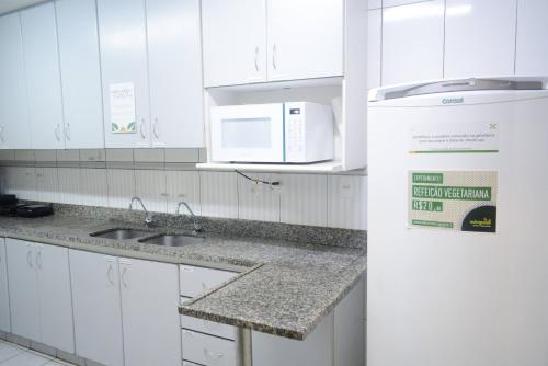 a white kitchen with a sink and a microwave at Br Hostel in Belo Horizonte