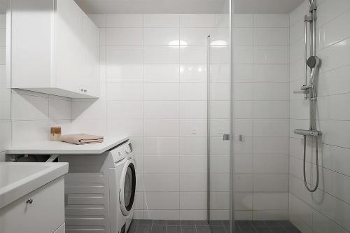 y baño blanco con ducha y lavadora. en Beautiful Central Apartment en Estocolmo