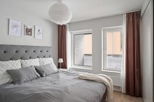 a bedroom with a large bed and two windows at Beautiful Central Apartment in Stockholm