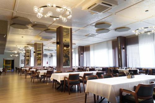 a dining room with tables and chairs and a chandelier at Hotel Montana Palace in Kru&scaron;evo