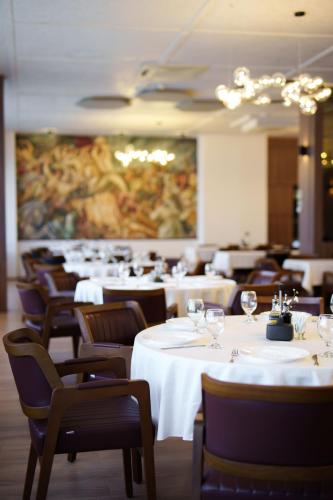 a dining room with white tables and chairs and a painting at Hotel Montana SPA in Kruševo