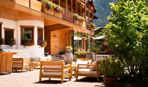 a patio with chairs and tables in front of a building at Corona Dolomites Hotel in Andalo