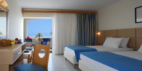 a hotel room with two beds and a view of the ocean at Kinetta Beach Resort and Spa in Kineta