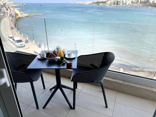 un tavolo con un piatto di cibo sopra accanto a una finestra di Dearborn Seafront a San Pawl il-Baħar