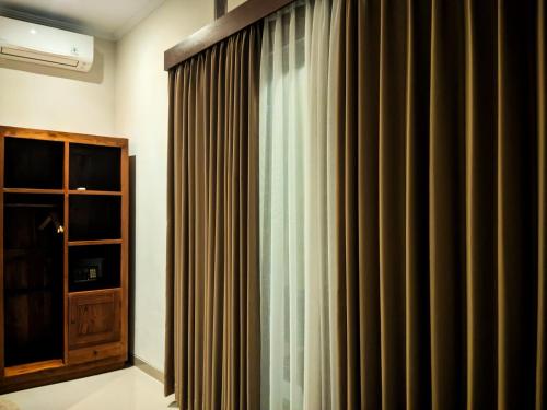 a room with a curtain and a cabinet at Griya Alit Guest House in Ketewel