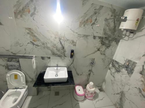 a white bathroom with a sink and a toilet at Om Paradise in Ujjain