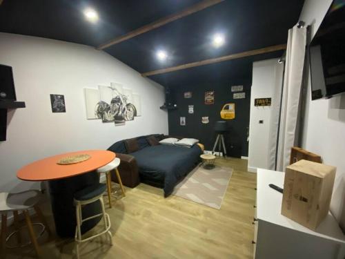 een woonkamer met een bed en een tafel bij Studio style biker avec parking fermé in Izon