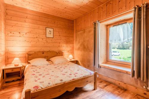 Bett in einem Holzzimmer mit Fenster in der Unterkunft Le Gîte des Cascades in Sixt