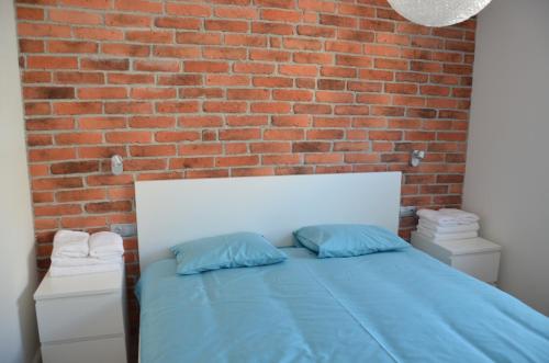 グダニスクにあるApartament na Starówce Grobla Iのレンガの壁のベッドルーム1室、青い枕付きのベッド1台が備わります。