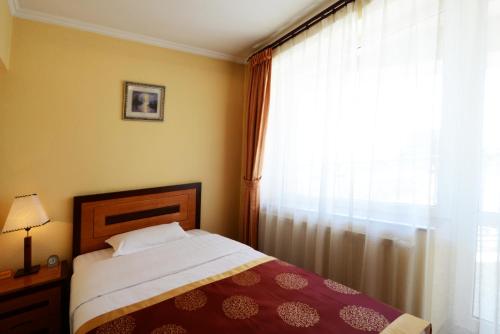 a bedroom with a bed next to a window at Narantuul Hotel in Ulaanbaatar