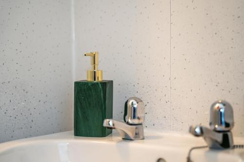 a bathroom sink with two faucets and a mirror at Cosmopolitan Comforts Flat in Coventry