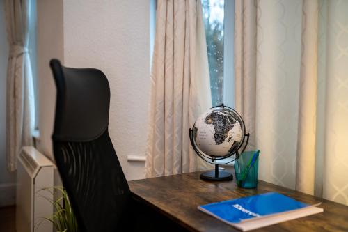 a desk with a globe sitting on top of it at Cosmopolitan Comforts Flat in Coventry