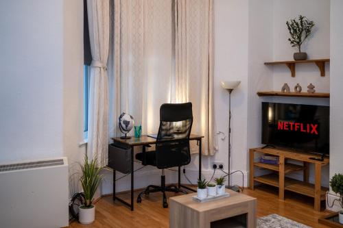 a living room with a tv and a chair and a table at Cosmopolitan Comforts Flat in Coventry