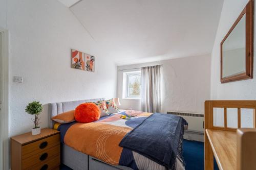 a bedroom with a bed with an orange pillow on it at Cosmopolitan Comforts Flat in Coventry