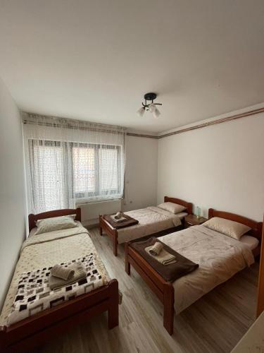 a room with three beds and two tables in it at Apartmani Dora Leskovac in Leskovac