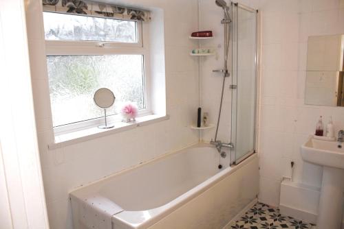 a bathroom with a tub and a sink and a window at Aderyn Mawr Cottage in Blaina