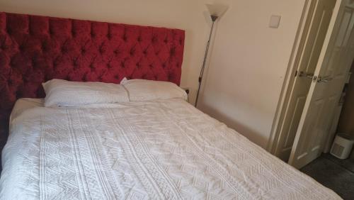 a bed with a red padded headboard and white sheets at Beautiful 3-Bed House in Lekki in Ikota