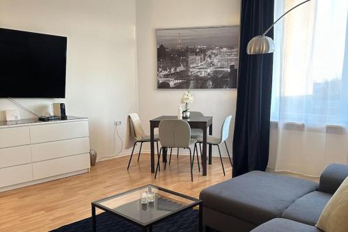 un soggiorno con divano e tavolo con sedie di City Apartment am Ku'damm & ICC Messe/Free Parking a Berlino