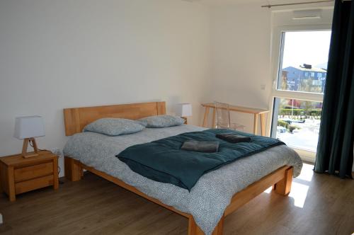 a bedroom with a bed and a large window at Entre Plage et Ports, Le 49 - avec balcon 4 étoiles in Courseulles-sur-Mer