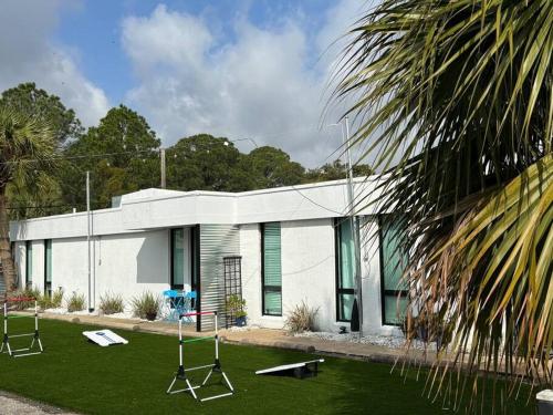 un bâtiment blanc avec des balançoires devant dans l'établissement Livin Right Sail Loft: pickleball, basketball, close 2 the fun!, à Fort Walton Beach