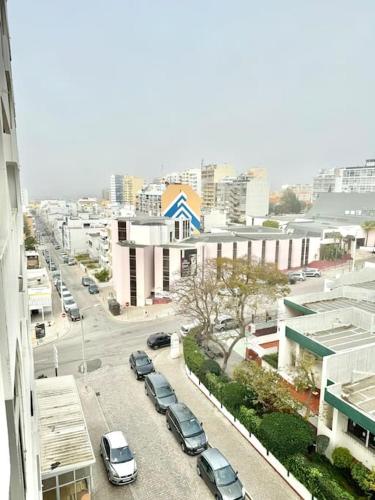 a city street with cars parked in a parking lot at Apartamento Faro - T3 in Faro