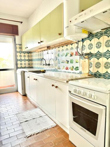 a kitchen with white cabinets and a stove top oven at Apartamento Faro - T3 in Faro